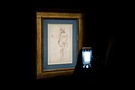 A framed drawing hanging on the wall and someone taking a photo of it with their phone